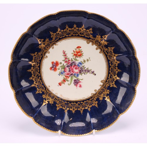 82 - A Worcester lobed dish, painted with a vignette of colourful flowers within scrolling gilt foliage, ... 