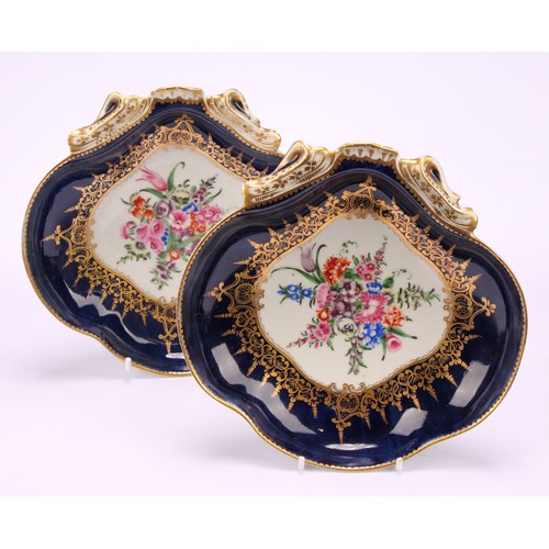 57 - A pair of Worcester shell shaped dishes, painted with a vignette of colourful flowers within scrolli... 