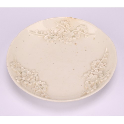 45 - A Bow blanc de chine shaped circular saucer, typically applied with blossoming prunus, 11cm diameter... 