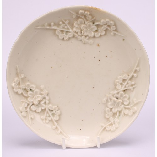 45 - A Bow blanc de chine shaped circular saucer, typically applied with blossoming prunus, 11cm diameter... 