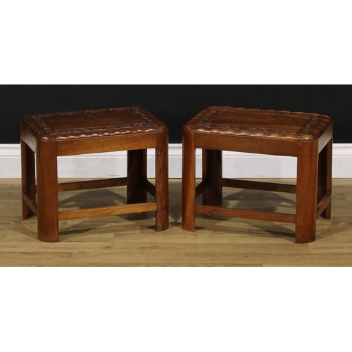 1545 - A pair of Art Deco period teak low tables, each carved with a border of flowers and foliage, 34cm hi... 