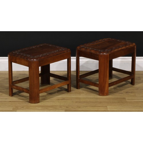 1545 - A pair of Art Deco period teak low tables, each carved with a border of flowers and foliage, 34cm hi... 