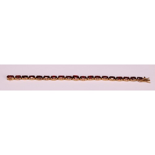 945 - A garnet bracelet, set with a continuous band of nineteen graduated oval cut stones, claw set, unmar... 