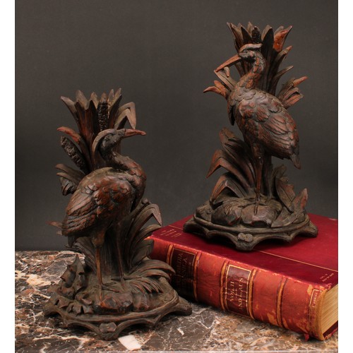 1377 - Treen - a pair of Black Forest candlesticks, carved as herons among reeds, arched bases, each 31cm h... 