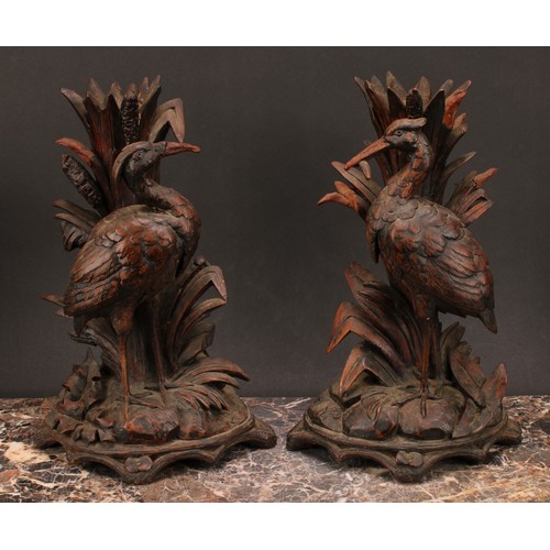 1377 - Treen - a pair of Black Forest candlesticks, carved as herons among reeds, arched bases, each 31cm h... 