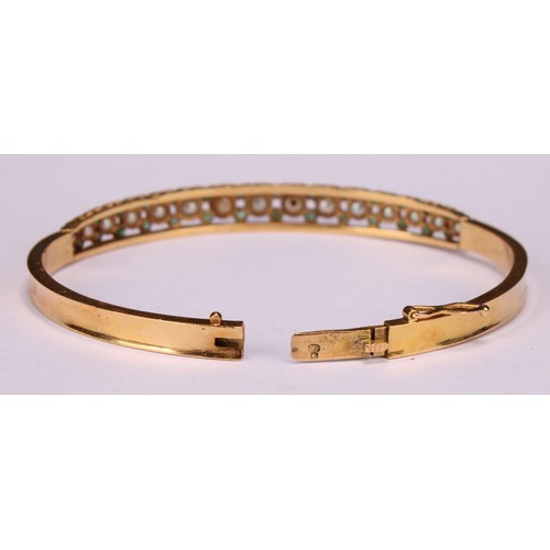 957 - An 18ct gold hinged bangle, set with 15 graduated pearls, each flanked and divided by pairs of small... 