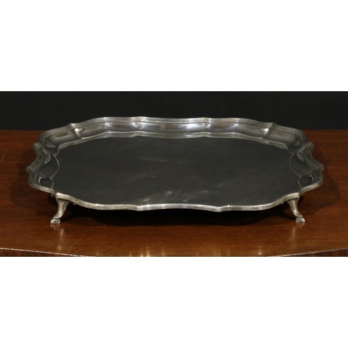 652 - A George III style silver salver, pie crust border, four scrolling supports terminating in hoof feet... 