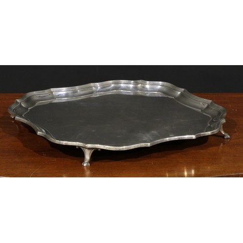 652 - A George III style silver salver, pie crust border, four scrolling supports terminating in hoof feet... 