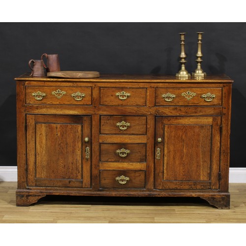 1194 - A George III oak low dresser, rectangular top above an arrangement of drawers and a pair of panel do... 