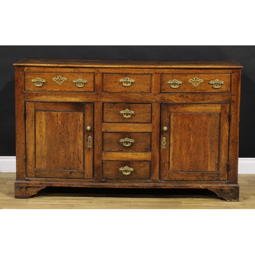 1194 - A George III oak low dresser, rectangular top above an arrangement of drawers and a pair of panel do... 