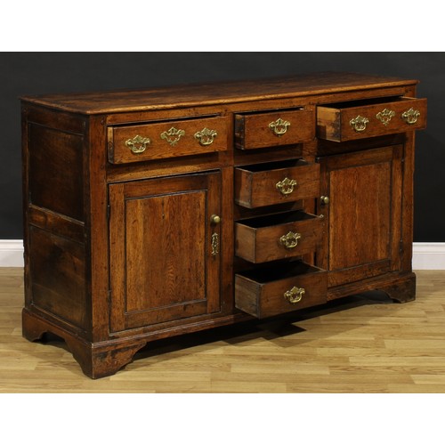 1194 - A George III oak low dresser, rectangular top above an arrangement of drawers and a pair of panel do... 