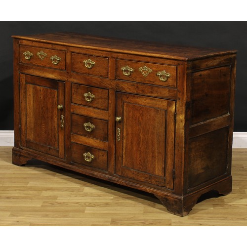 1194 - A George III oak low dresser, rectangular top above an arrangement of drawers and a pair of panel do... 