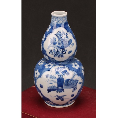 208 - A Chinese double gourd vase, painted in tones of underglaze blue with a scholar's table and precious... 