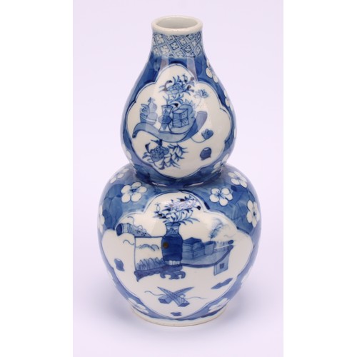 208 - A Chinese double gourd vase, painted in tones of underglaze blue with a scholar's table and precious... 