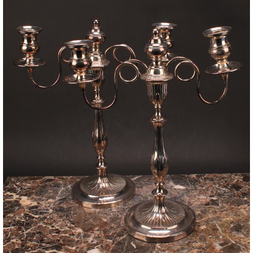 552 - A pair of George III Old Sheffield Plate two-light table candelabra, campana sconces, slender balust... 