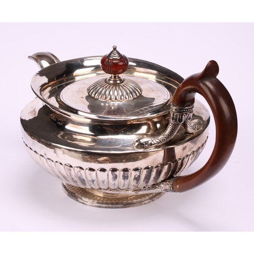 654 - A George IV silver half-fluted lamp shaped teapot, in the Regency taste, flush-hinged cover, scroll-... 