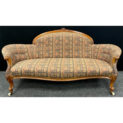 1449 - A Victorian walnut sofa, arched cresting carved with flowers and scrolling leaves, stuffed-over upho... 