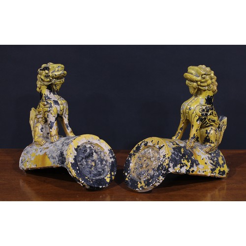 253 - A pair of Chinese earthenware ridge tiles, monochrome glazed in tones of mottled yellow, crested by ... 