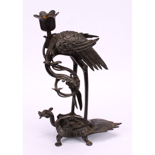 277 - A Chinese dark patinated bronze candlestick, cast as a crane standing upon a turtle, 24cm high, six ... 