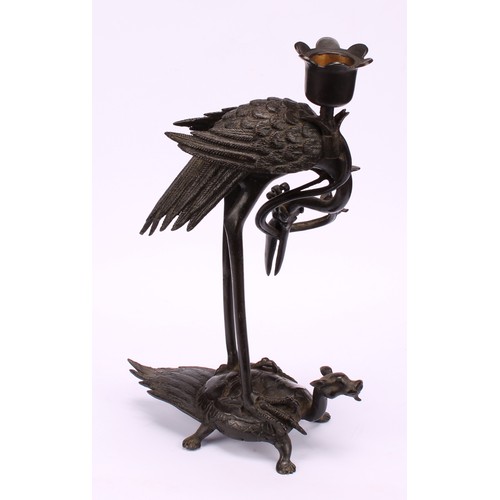 277 - A Chinese dark patinated bronze candlestick, cast as a crane standing upon a turtle, 24cm high, six ... 