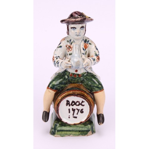 9 - A Dutch Delft figure, of a man drinking wine, seated upon a barrel inscribed Root 1776, 13cm high