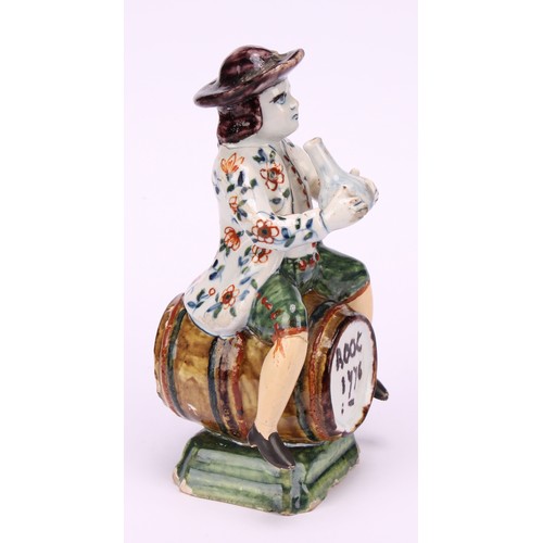 9 - A Dutch Delft figure, of a man drinking wine, seated upon a barrel inscribed Root 1776, 13cm high