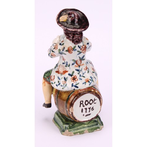 9 - A Dutch Delft figure, of a man drinking wine, seated upon a barrel inscribed Root 1776, 13cm high