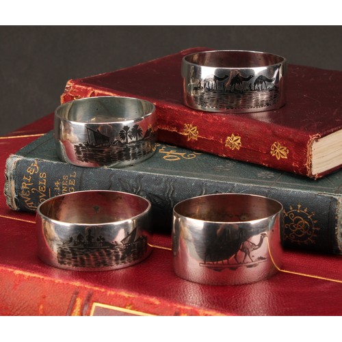 677 - A harlequin suite of four Iraqi silver and niello napkin rings, decorated with genre scenes and land... 