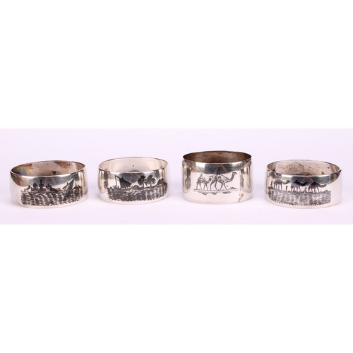 677 - A harlequin suite of four Iraqi silver and niello napkin rings, decorated with genre scenes and land... 