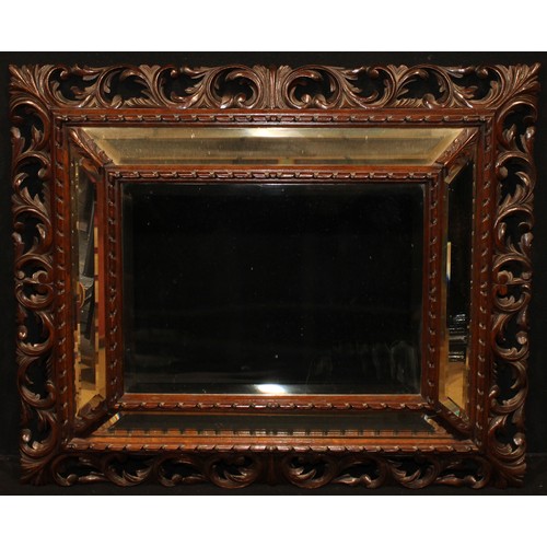 1888 - A late 19th century oak looking glass, central bevelled mirror plate within a conforming cushion bor... 