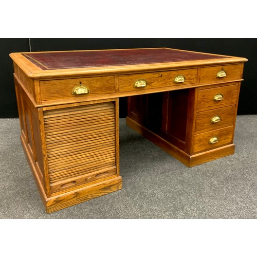 184 - An early 20th century oak partners desk, the rounded rectangular top with inset red leather writing ... 