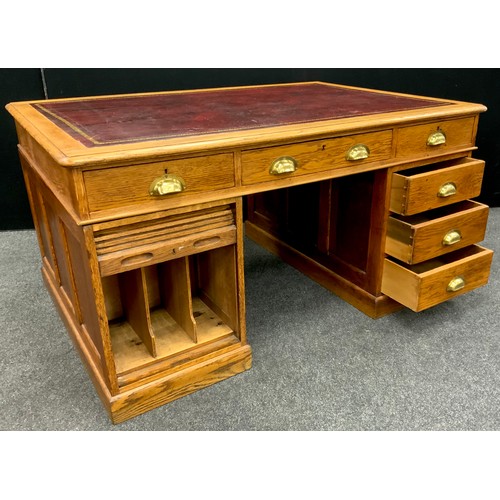 184 - An early 20th century oak partners desk, the rounded rectangular top with inset red leather writing ... 