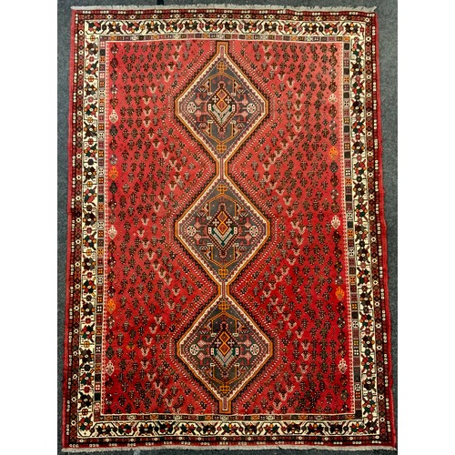 204 - A Persian rug or carpet, central row of three medallions in tones of brown, orange, red and cream on... 