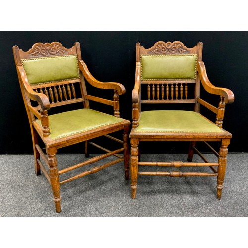 205 - A pair of Edwardian Arts and Crafts oak armchairs, the shaped and carved top rail above a green leat... 