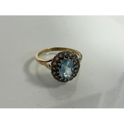 310 - A 9ct yellow and white gold ring set with a central oval blue topaz surrounded by halo of Round cut ... 