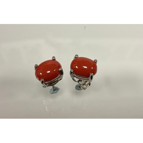 313 - A Pair of oval cabochon coral stud earrings, in silver mounts.