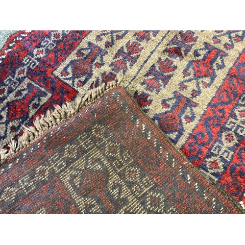 238 - A mid 20th century Afghan type woollen rug, knotted in tones of red, deep blue, and grey, 120cm x 76... 