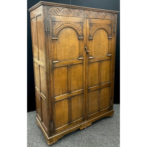 242 - A priory style carved oak double wardrobe, 182.5cm high x 126.5cm wide x 55.5cm deep.