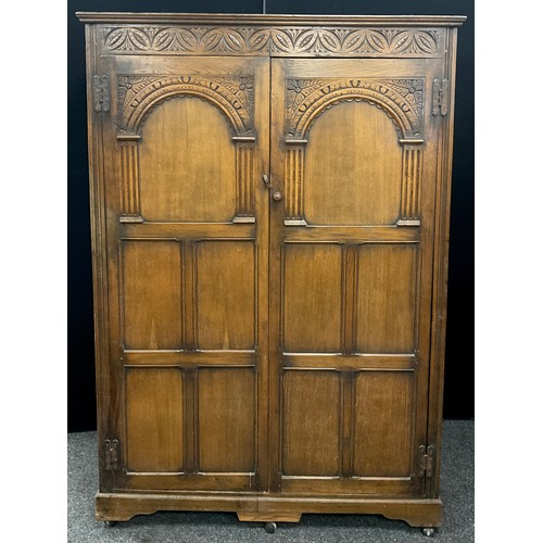 242 - A priory style carved oak double wardrobe, 182.5cm high x 126.5cm wide x 55.5cm deep.