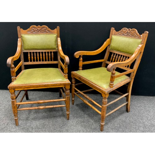 229A - A pair of Edwardian Arts and Crafts oak armchairs, the shaped and carved top rail above a green leat... 