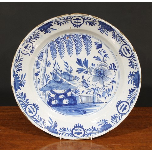 20A - An 18th century Dutch Delft charger, painted in polychrome, with flowers, tree and trellis, 34.5cm d... 