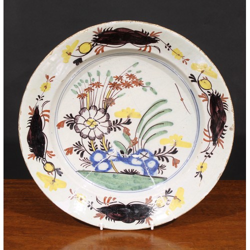 20A - An 18th century Dutch Delft charger, painted in polychrome, with flowers, tree and trellis, 34.5cm d... 