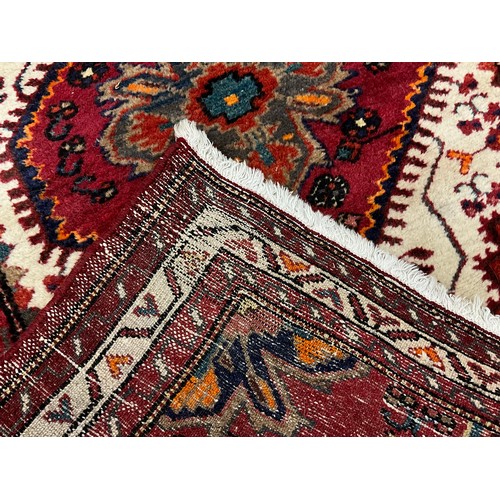 97 - A Persian Shiraz type rug / carpet, hand-knotted in deep red, indigo, turquoise, orange, and white, ... 