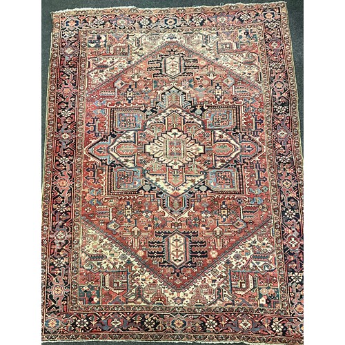 142 - A Persian Heriz type rug / carpet, hand-knotted with a central diamond shaped medallion, within an a... 