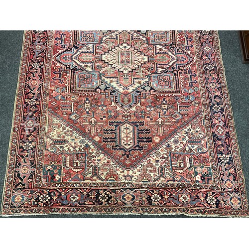 142 - A Persian Heriz type rug / carpet, hand-knotted with a central diamond shaped medallion, within an a... 