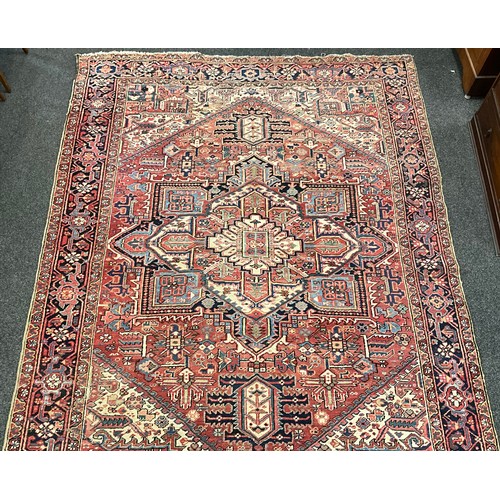 142 - A Persian Heriz type rug / carpet, hand-knotted with a central diamond shaped medallion, within an a... 