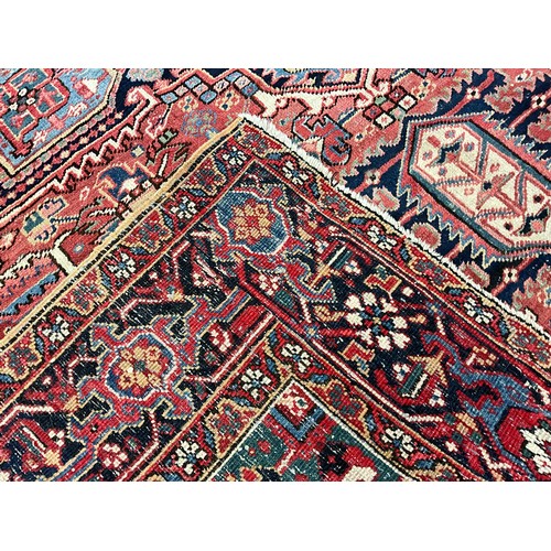 142 - A Persian Heriz type rug / carpet, hand-knotted with a central diamond shaped medallion, within an a... 