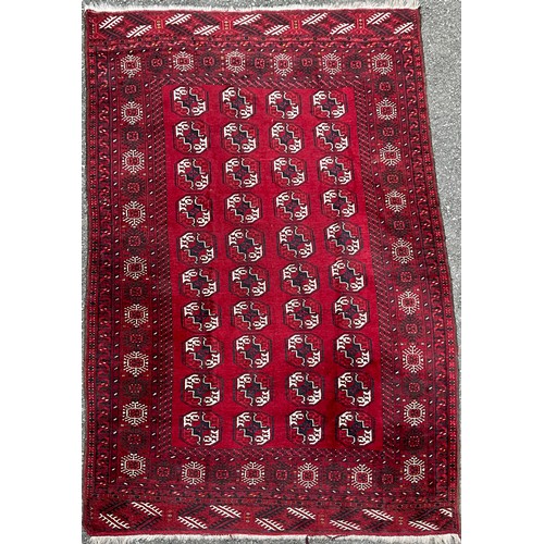 192 - A Tekke Torkman hand-knotted rug, with four bands of geometric guls, in white, black and blue on red... 