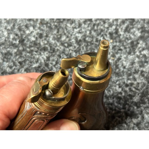 2422 - Pair of Copper Pistol Powder Flasks. One unmarked with a embossed floral design 110mm in length. The... 