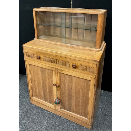 101 - A 20th century light oak Priory style side cabinet, two door glazed top above frieze drawer and pair... 